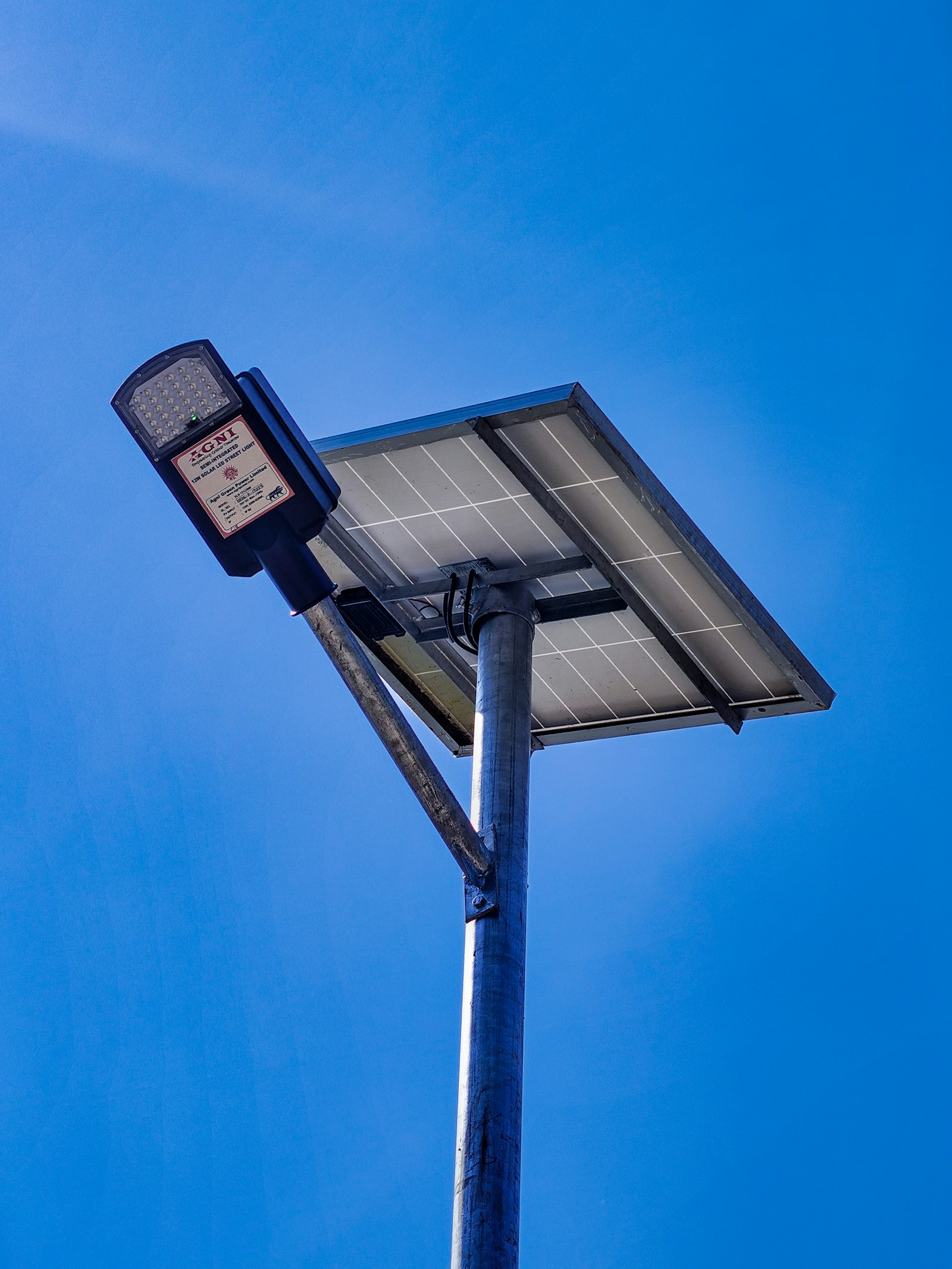 Solar-powered street light with panel and LED fixture against a clear sky